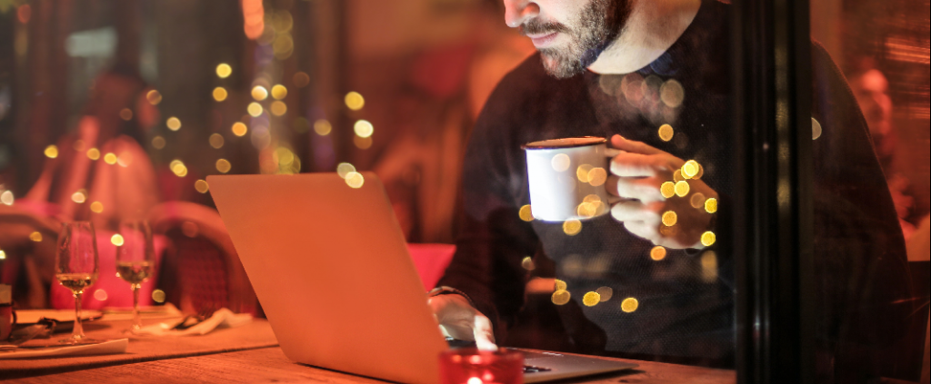 Bearded guy drinking coffee and watching videos on demand in a lovely restaurant