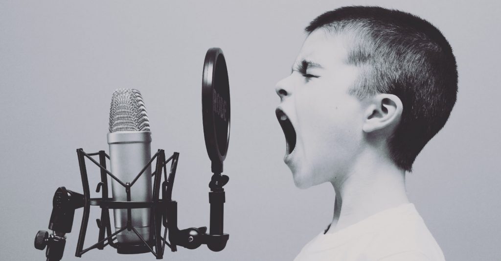 Kid yelling into studio microphone while podcasting